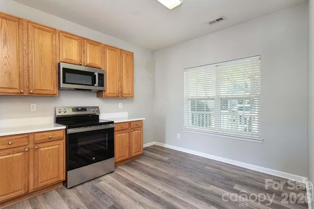 a kitchen with granite countertop wooden cabinets a stove a microwave and a window