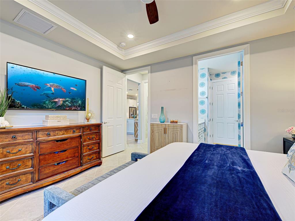 13836 Campoleone Street Venice, FL 34293 - Photo 25 of 99 a spacious bedroom with a large bed and a flat screen television