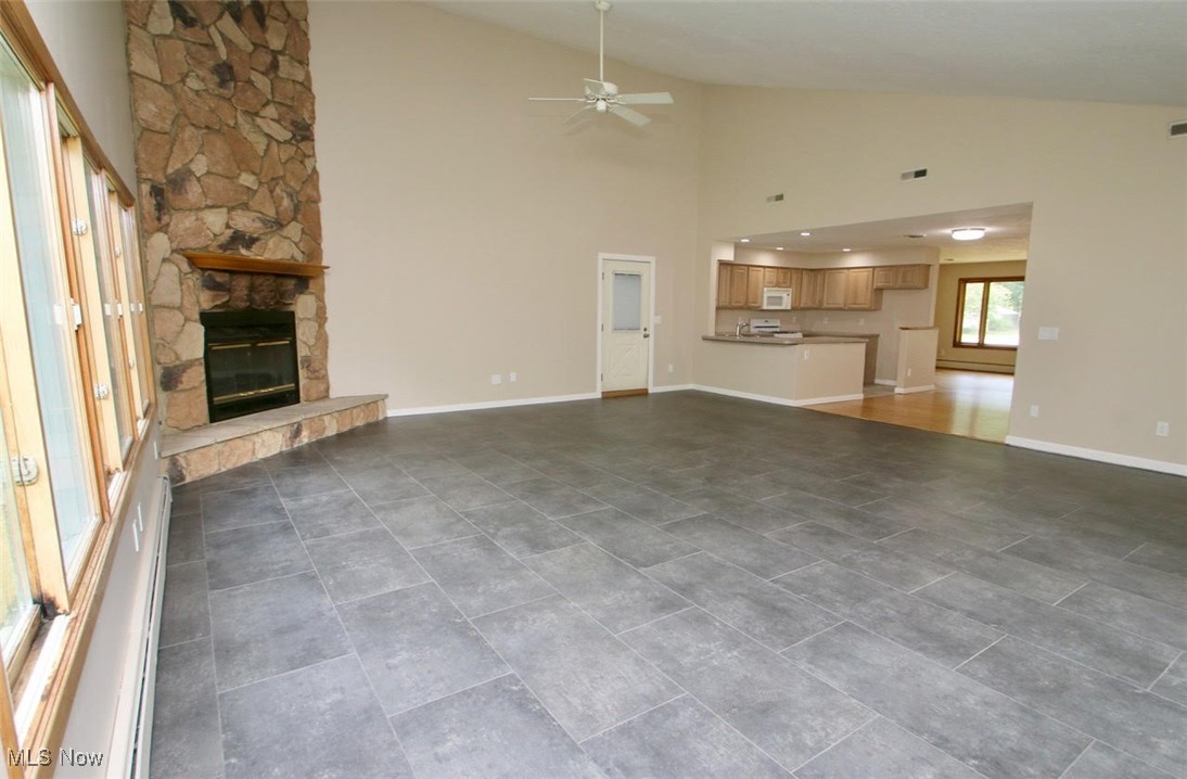 7958 Bellflower Road Mentor, OH 44060 - Photo 15 of 34 Unfurnished living room with a ceiling fan, a stone fireplace, and high vaulted ceiling