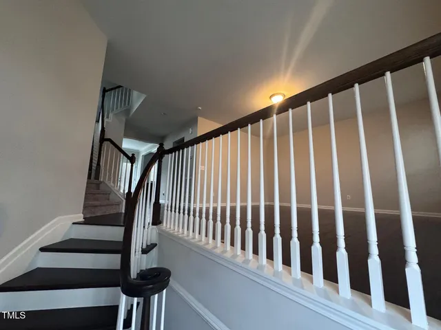 a view of staircase with railing and white walls