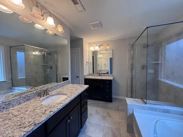 a bathroom with a granite countertop sink a mirror and a shower