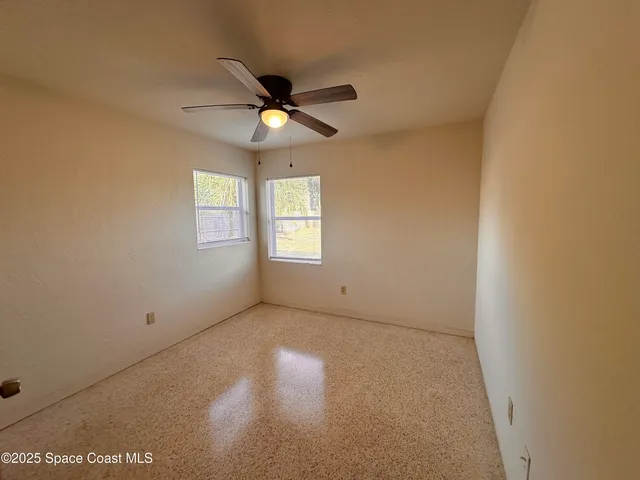 an empty room with windows and fan