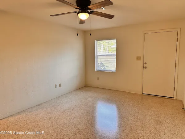 an empty room with a window and a fan