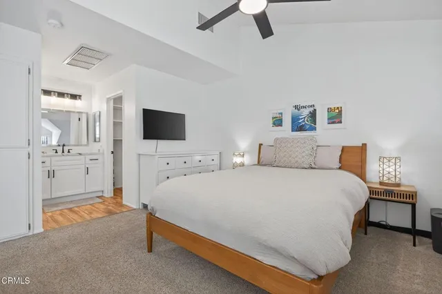 a large bedroom with a bed and flat tv screen on the dresser