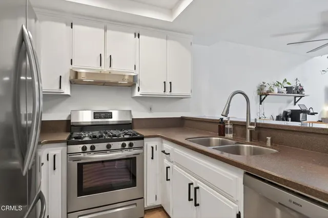 a kitchen with stainless steel appliances granite countertop a sink a stove and cabinets