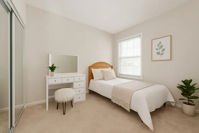 a bedroom with a bed and a potted plant on the dresser