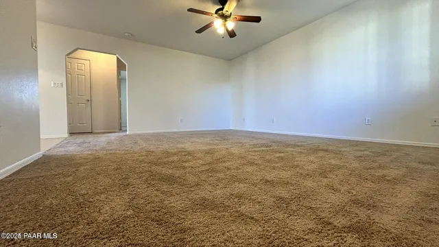 an empty room with a ceiling fan and window