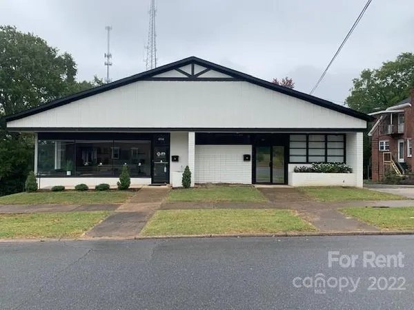 a view of a house with a yard and large parking space