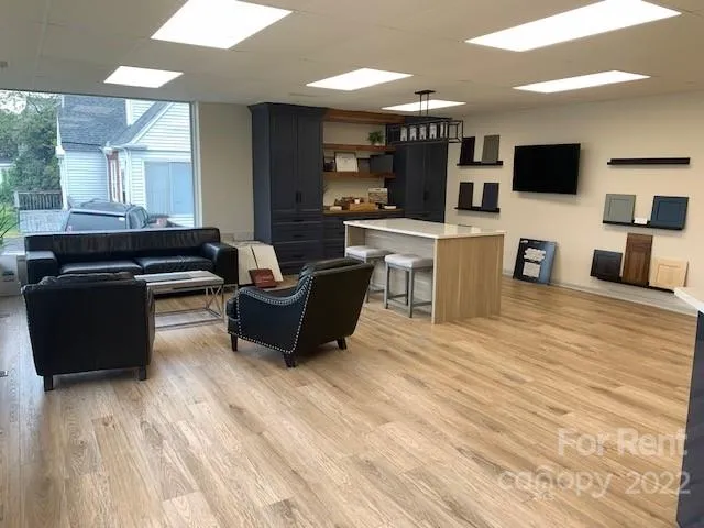 a living room with furniture a flat screen tv and kitchen view