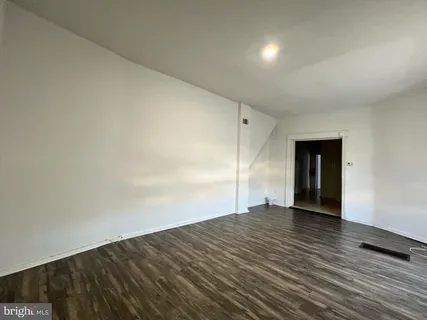 a view of an empty room with wooden floor and closet