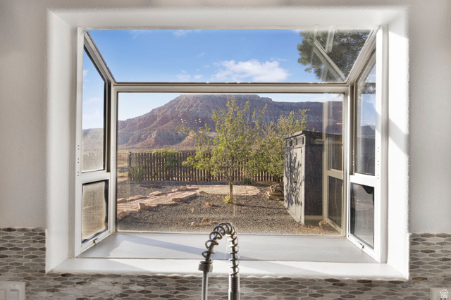 1440 West 100 South Virgin, UT 84779 - Photo 14 of 45 Expansive kitchen window featuring a mountain backdrop, a fenced yard, and a pull-down faucet