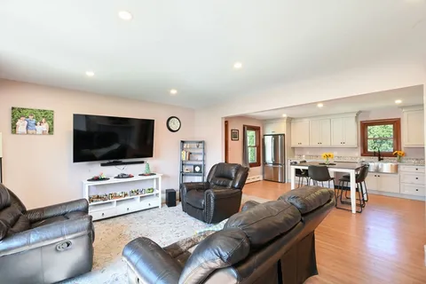 a kitchen with stainless steel appliances kitchen island granite countertop a stove a sink a dining table and chairs with wooden floor