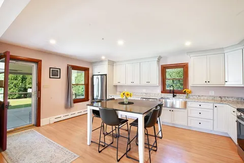 a kitchen with stainless steel appliances a stove a sink dishwasher a refrigerator with a dining table and chairs