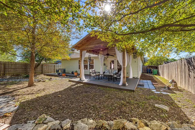 a view of a backyard with table and chairs under a large tree