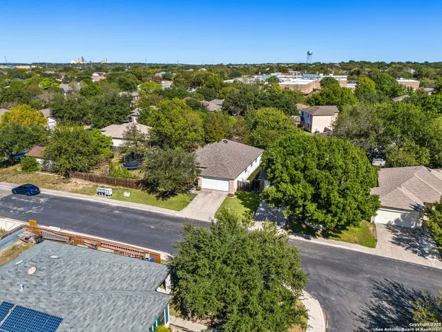 an aerial view of residential houses with outdoor space and trees