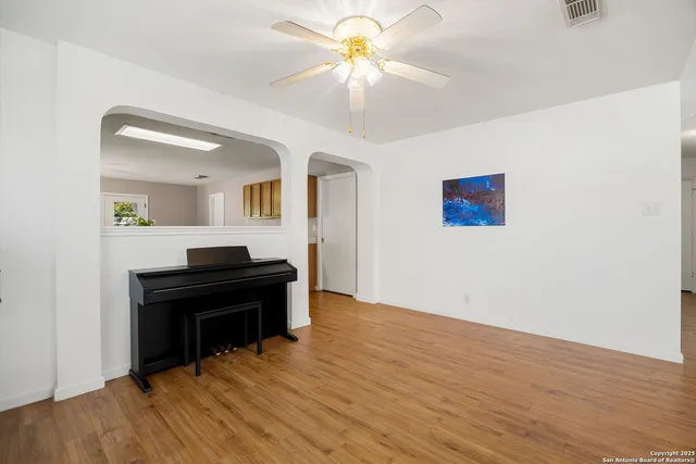 a view of a workspace with wooden floor and a chandelier fan