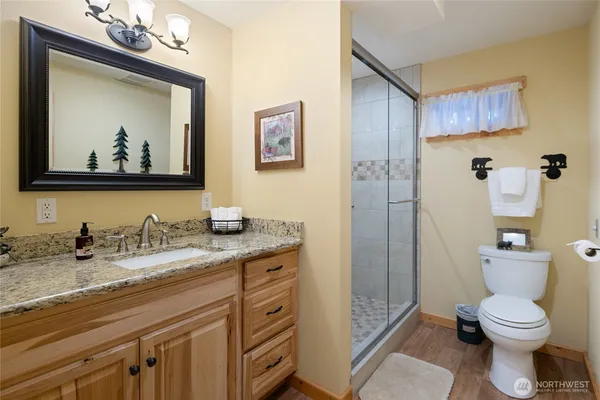 a bathroom with a granite countertop sink toilet and painting on the wall
