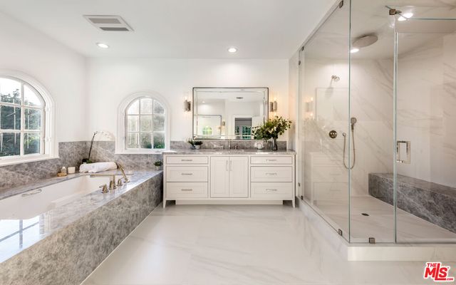 a large bathroom with a tub a sink shower and mirror