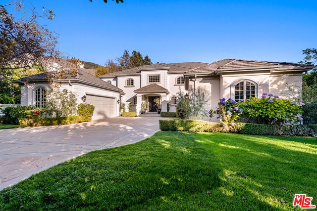 a front view of a house with a yard and potted plants