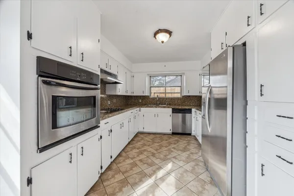a kitchen with stainless steel appliances kitchen island granite countertop a refrigerator a stove and a sink