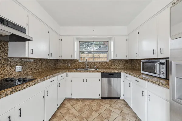 a kitchen with granite countertop white cabinets white stainless steel appliances with a sink and dishwasher