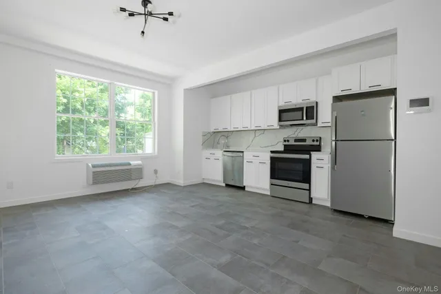 a kitchen with a refrigerator a stove top oven a sink and a window