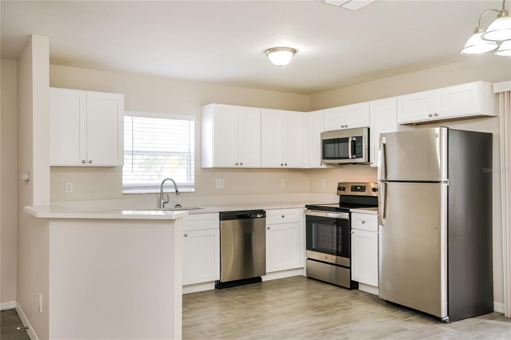 146 Hidden Lk Loop Haines City, FL 33844 - Photo 5 of 16 a kitchen with stainless steel appliances granite countertop a refrigerator a sink a stove a microwave and white cabinets