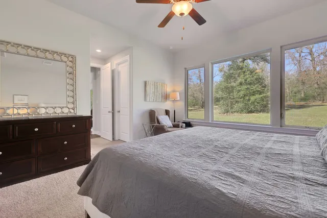 a spacious bedroom with a large bed and ceiling fan