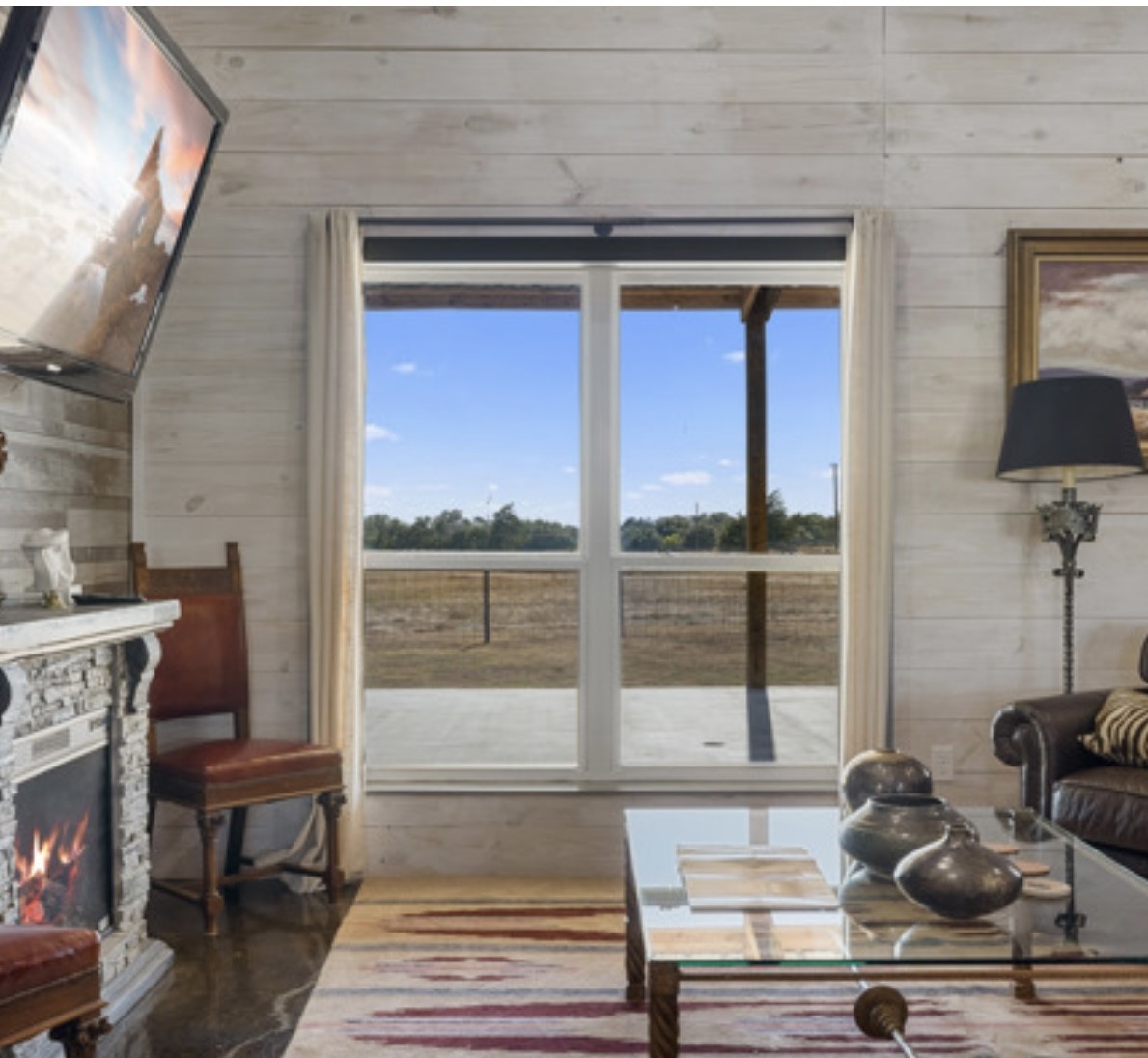 7210 Goehring Road Ledbetter, TX 78946 - Photo 10 of 47 a living room with furniture a fireplace and a floor to ceiling window