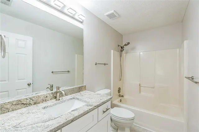 a bathroom with a granite countertop sink a toilet and a large mirror