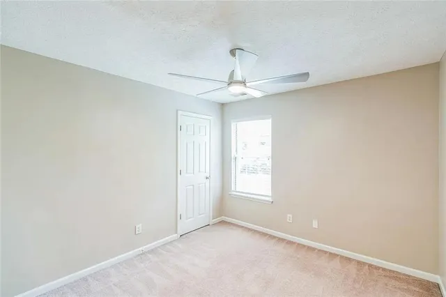 an empty room with a chandelier fan and windows