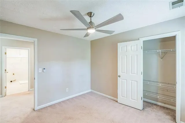 an empty room with closet and a ceiling fan