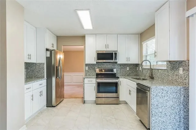 a kitchen with stainless steel appliances granite countertop a refrigerator stove and sink