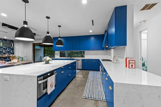 a kitchen with stainless steel appliances granite countertop a sink a stove and a wooden floors