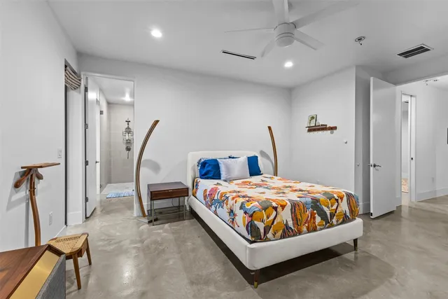 a bedroom with a bed a ceiling fan and a wooden floor