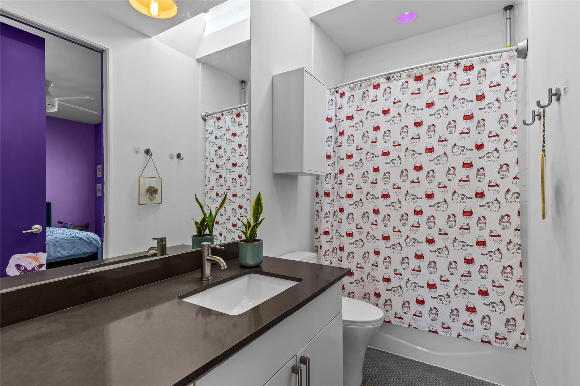 5704 Driftwood Drive Austin, TX 78731 - Photo 29 of 40 a bathroom with a granite countertop sink a toilet and a shower curtain