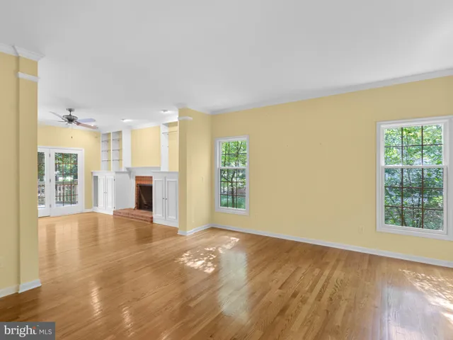 a view of an empty room with window and wooden floor