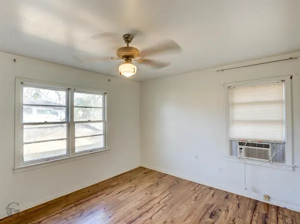 a view of empty room with wooden floor and fan