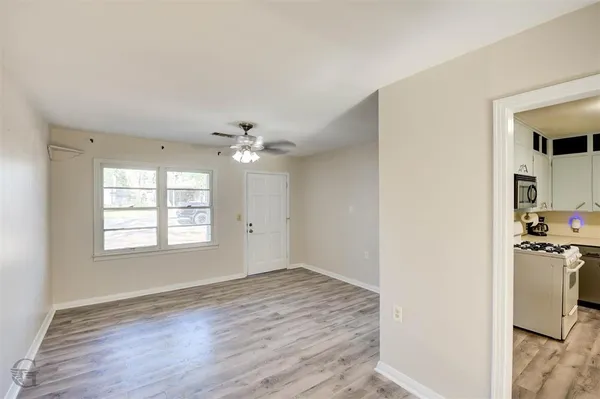 a view of empty room with wooden floor and fan