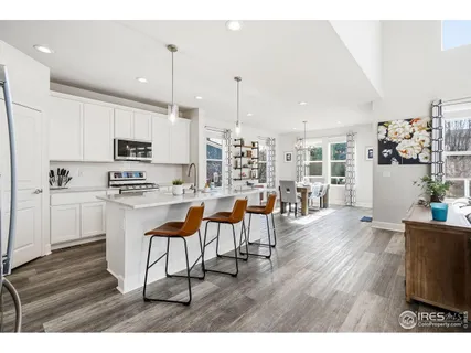 a kitchen with stainless steel appliances kitchen island granite countertop a table chairs and a refrigerator
