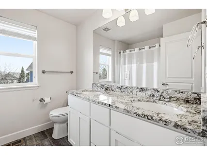 a bathroom with a granite countertop sink toilet and mirror