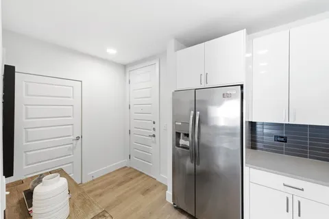 a view of a refrigerator in kitchen and an empty room