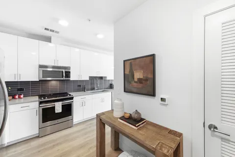 a kitchen with stainless steel appliances white cabinets and wooden floor