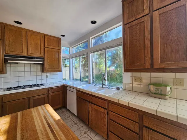 a kitchen with stainless steel appliances granite countertop wooden cabinets a sink and a large window