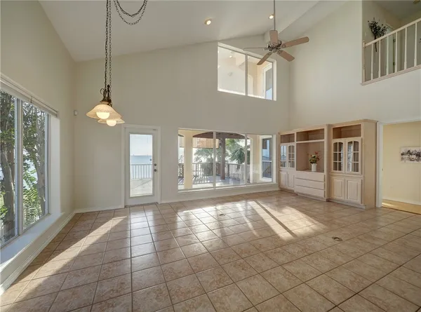 a view of an empty room with a window and chandelier fan
