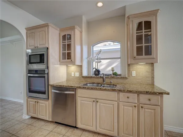 a kitchen with stainless steel appliances granite countertop a sink and dishwasher a refrigerator with white cabinets