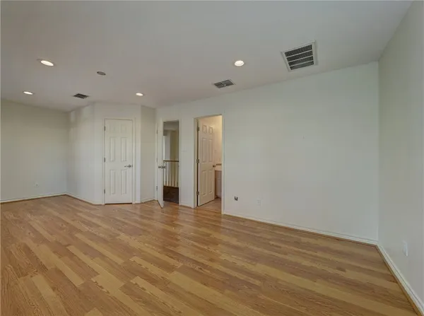 a view of a big room with wooden floor and windows