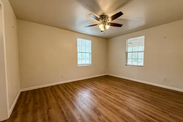 a view of an empty room with chandelier and wooden floor