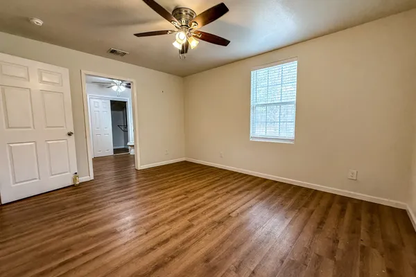 a view of an empty room with wooden floor and a window