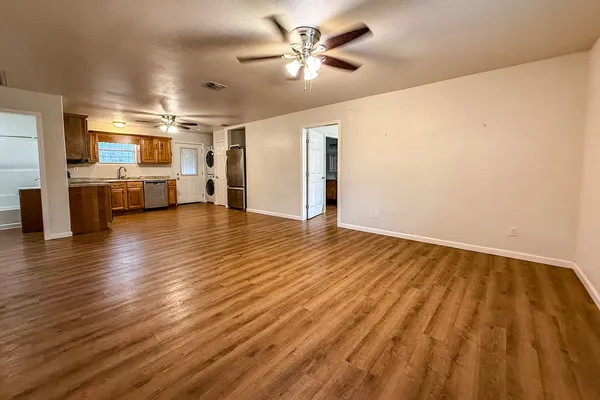 an empty room with wooden floor and a ceiling fan